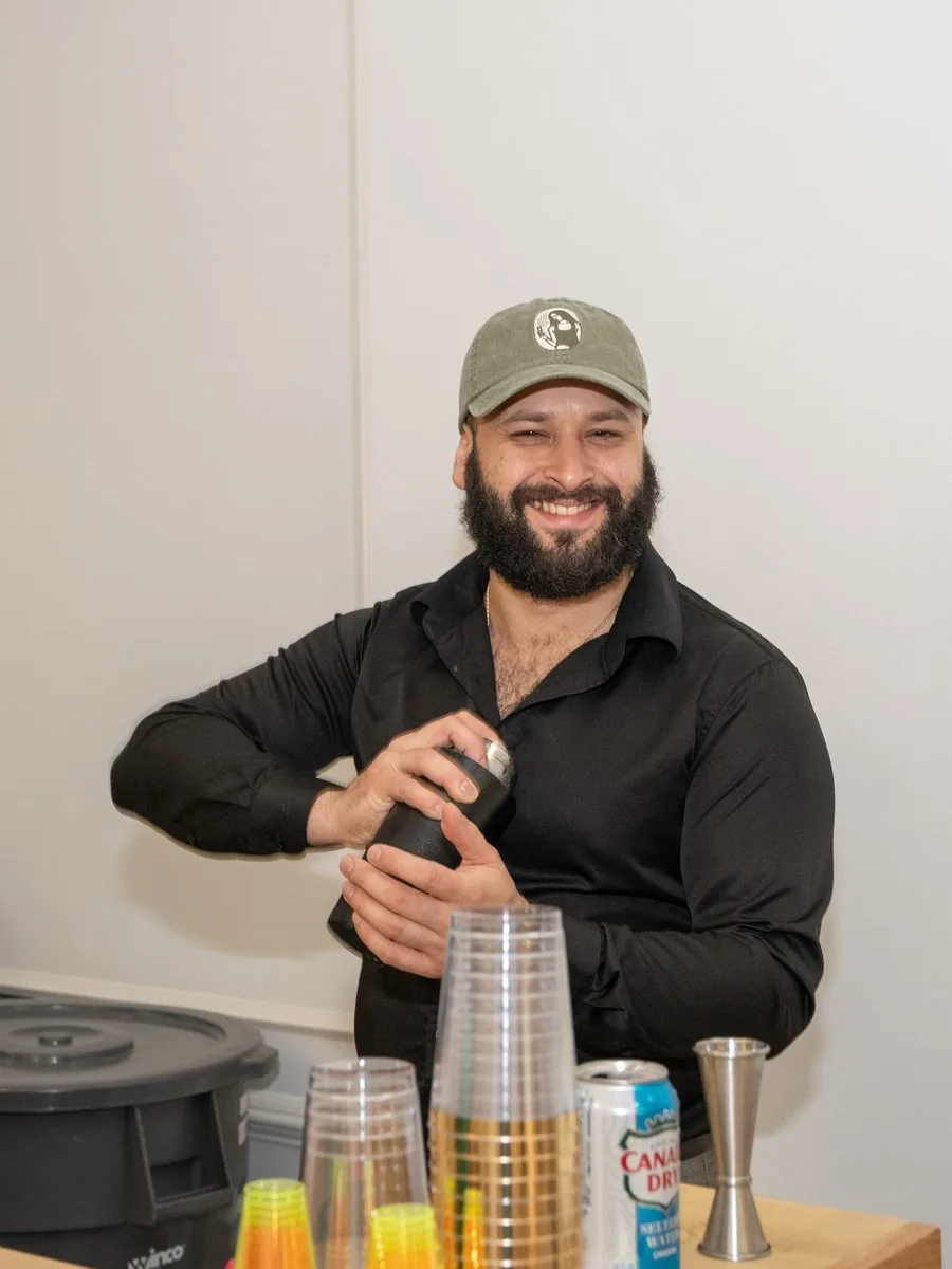 Hernan Trujillo shaking a cocktail behind a Luxe & Libations event bar